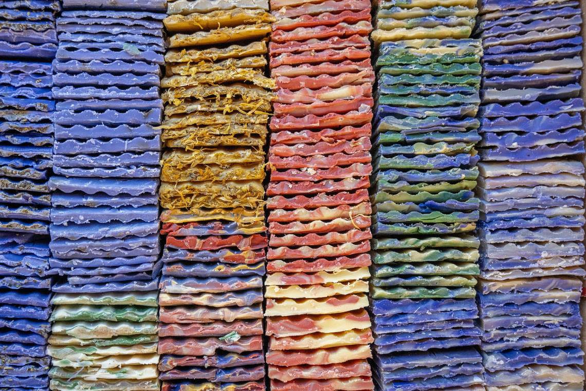 Soap shavings from leftover batches are seen organized by color near the order fulfillment area at Indigo Wild soap manufacturing facility. The shavings are repurposed as samples or used to make the company’s 3125 bar.