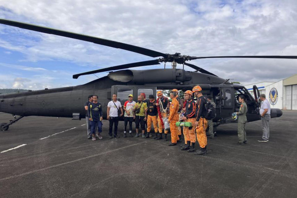 In this handout photo provided by the Civil Aviation Authority of the Philippines, rescuers stand beside a helicopter as they prepare their search for passengers of a Cessna 340 aircraft with registry number RP-C2080 at Camalig town, Albay province, southeast of Manila, Philippines on Tuesday Feb. 21, 2023. The wreckage of a small plane carrying two Filipino pilots and two Australian passengers was identified Tuesday on one of the Philippines' most active volcanoes, officials said. (Civil Aviation Authority of the Philippines via AP)