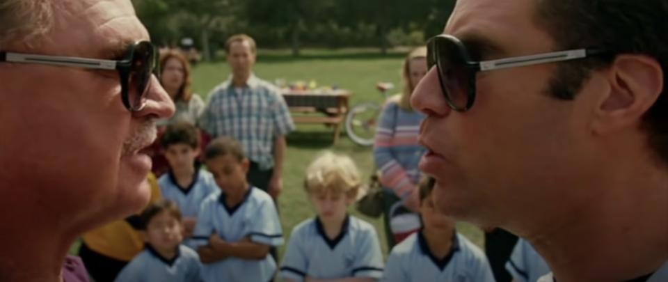 two men argue in front of a children's soccer team