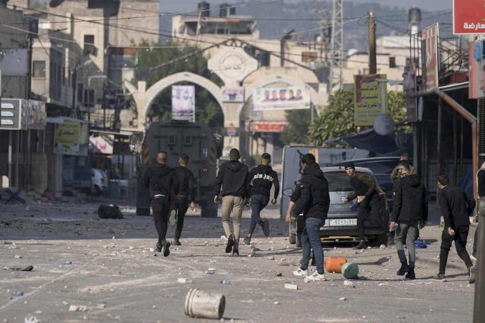 Palestinians clash with Israeli forces following an army raid in the West Bank city of Jenin, Thursday, Jan. 26, 2023. Israeli forces killed at least nine Palestinians, including a 60-year-old woman, and wounded several others during a raid in a flashpoint area of the occupied West Bank on Thursday, Palestinian health officials said, in one of the deadliest days in months of unrest. The Israeli military said it was conducting an operation to arrest a militant grouping linked to the Palestinian Islamic Jihad, which has major foothold in the camp. A gun battle erupted, during which the military said it was targeting militants involved in planning and carrying out attacks on Israelis. (AP Photo/Majdi Mohammed)