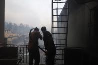 People try to extinguish a fire at a house in Rovies village on the island of Evia, about 160 kilometers (100 miles) north of Athens, Greece, Wednesday, Aug. 4, 2021. Greece evacuated people in boats from an island beach Wednesday amid heavy smoke from a nearby wildfire and fire crews fought elsewhere to keep flames away from the birthplace of the ancient Olympic Games as the country sweltered under a record heat wave. (AP Photo/Thodoris Nikolaou)