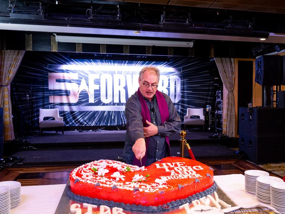 A person cutting a cake on Entertainment Cruise Productions' Star Trek cruise.