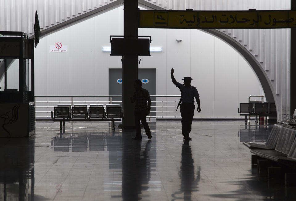 FILE - In this Aug. 20, 2011, file, photo taken on a government-organized tour, a guard waves to fellow officers in the main lobby of the international airport in Tripoli, Libya. The only functioning airport in Libya's capital suspended its operations after coming under attack Wednesday, Jan. 22, 2020, airport authorities said, despite a tenuous truce that world powers have pushed warring parties to respect. Authorities at Mitiga airport said six Grad missiles crashed into the tarmac. (AP Photo/Dario Lopez-Mills, File)