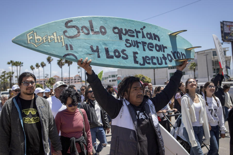 A demonstrator holding a bodyboard written in Spanish " They just wanted to surf and they were executed" protests the disappearance of foreign surfers in Ensenada, Mexico, Sunday, May 5, 2024. Mexican authorities said Friday that three bodies were recovered in an area of Baja California near where two Australians and an American went missing last weekend during an apparent camping and surfing trip. (AP Photo/Karen Castaneda)