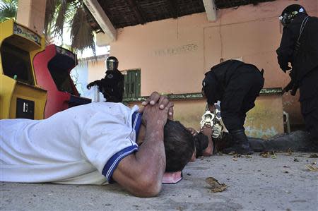 An inmate lies on the ground as a policeman holds handcuffs after a gunfight in the Tuxpan prison in Iguala, in the Mexican State of Guerrero January 3, 2014. REUTERS/Jesus Solano