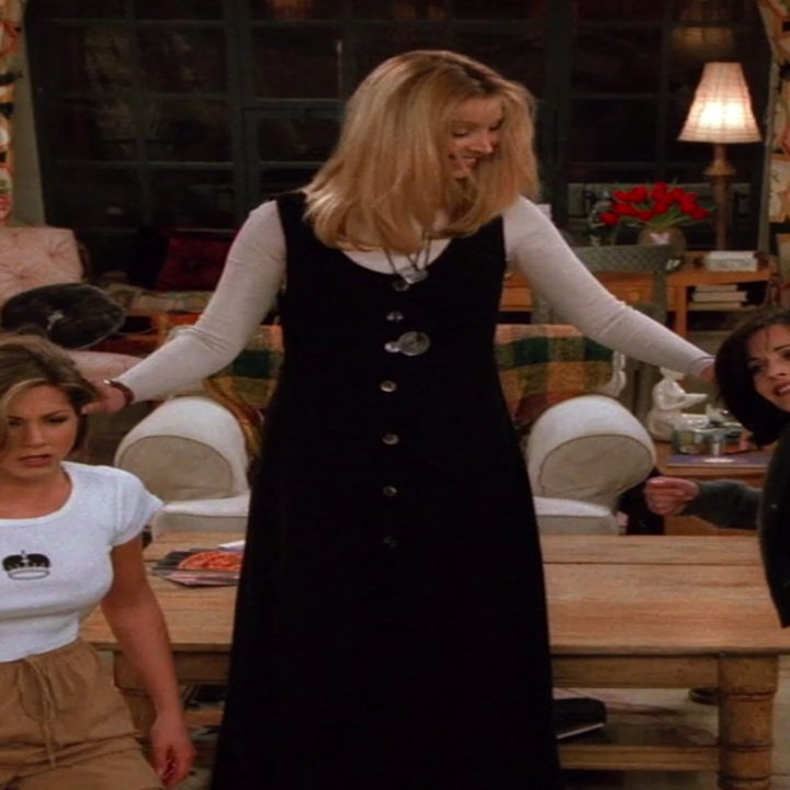 Phoebe wearing boots, a long dress, a long-sleeve shirt underneath, and necklaces