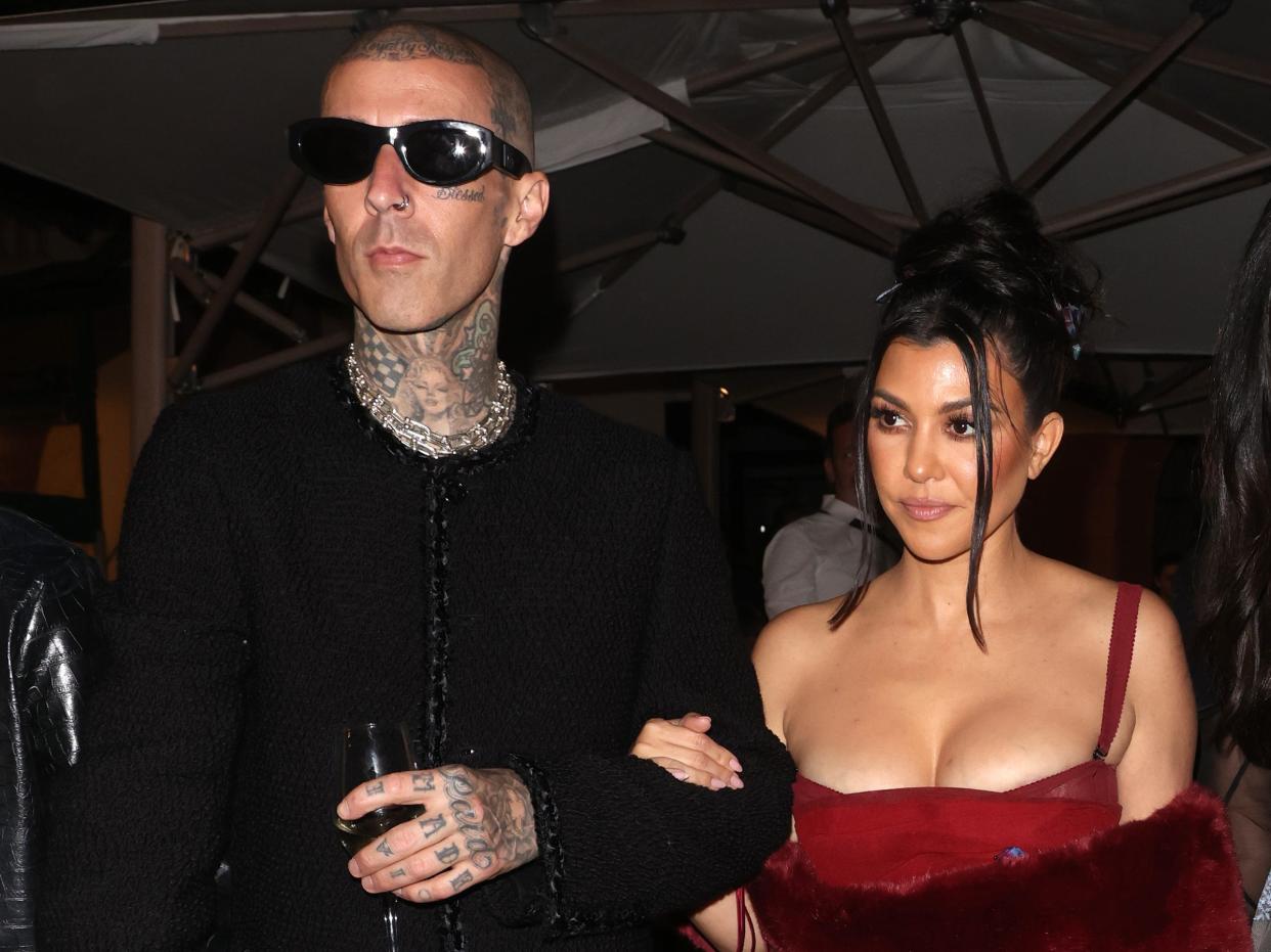 Travis Barker in all black and Kourtney Kardashian in all red