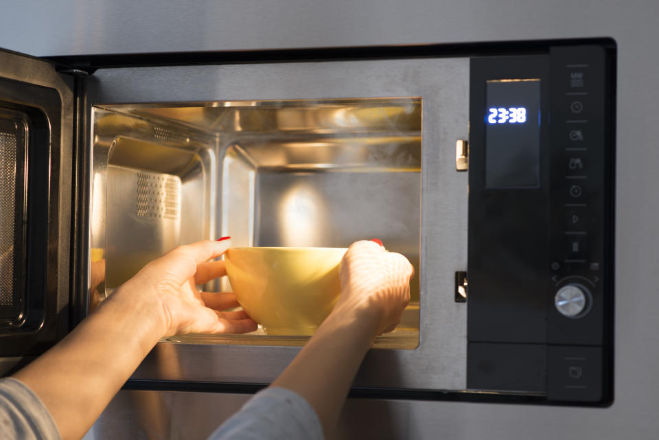 Woman at home heating food at microwave oven