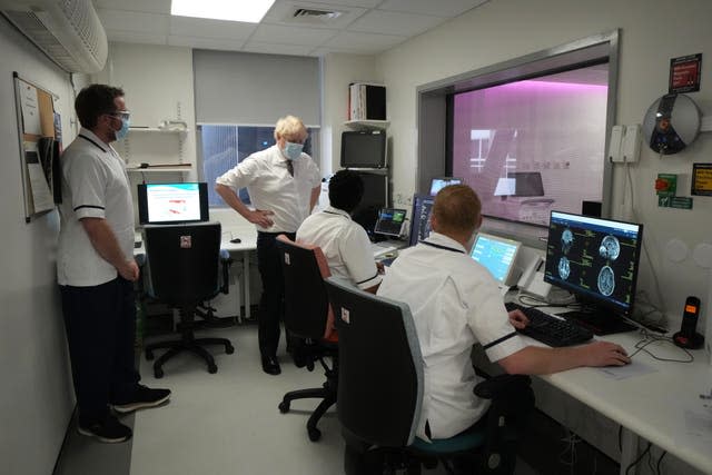 Prime Minister Boris Johnson speaks with staff as he views an MRI 