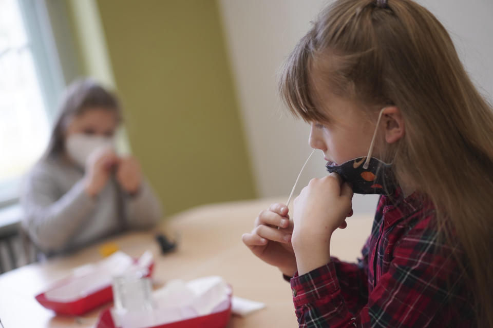 Students Zeynep, left, and Neele from the Fritz Karsen Community School take a Corona self-test before classes begin in Berlin, Germany, Monday, April 19, 2021. Berlin children must be tested for the Corona virus in schools starting today. (Joerg Carstensen/dpa via AP)