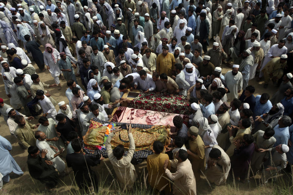 Relatives and mourners gather around the caskets of victims who were killed in Sunday's suicide bomber attack in the Bajur district of Khyber Pakhtunkhwa, Pakistan, Monday, July 31, 2023. Pakistan held funerals on Monday for victims of a massive suicide bombing that targeted a rally of a pro-Taliban cleric the previous day. (AP Photo/Mohammad Sajjad)