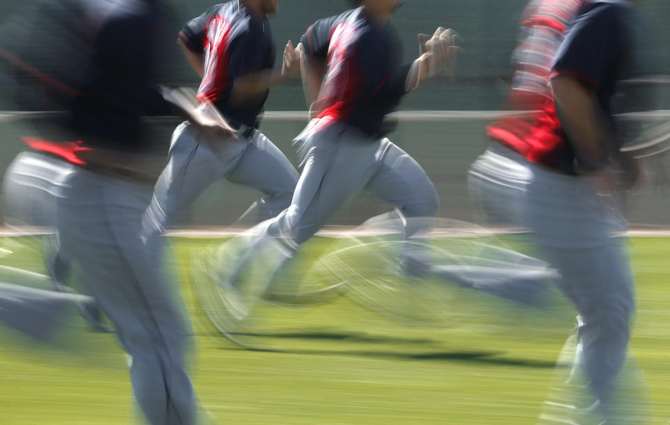 In this image taken with a slow shutter speed, Cleveland Indians players run during spring training baseball practice in Goodyear, Ariz., Thursday, Feb. 13, 2014. (AP Photo/Paul Sancya)