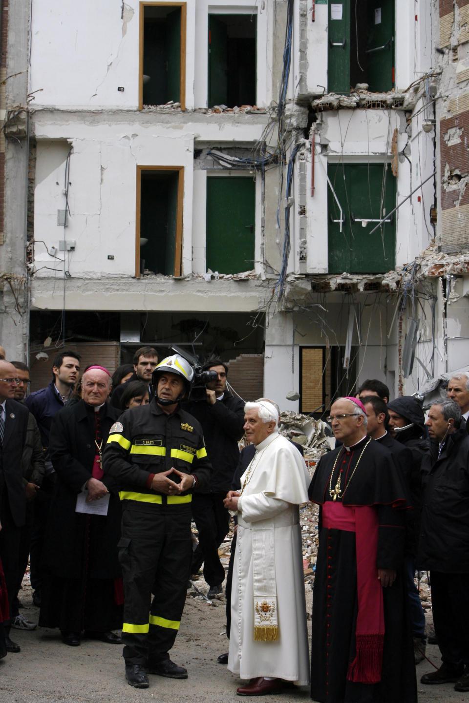 FILE - Pope Benedict XVI is flanked by a firefighter as he looks at a collapsed student dorm after an earthquake, in L'Aquila, central Italy, April 28, 2009. During a visit to the earthquake-ravaged city of L’Aquila, Benedict prayed at the tomb of Pope Celestine V, the hermit pope who stepped down in 1294 after just five months in office. (AP Photo/Alessandra Tarantino, File)