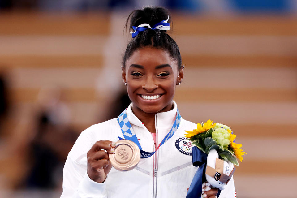 Simone Biles shows off her bronze medal at the Tokyo Olympics.