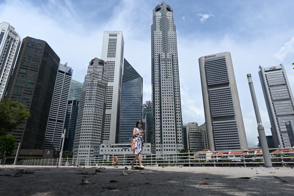 A woman walks past commercial buildings in the financial business district in Singapore on June 11, 2020, as the city state eased its partial lockdown restrictions aimed at curbing the spread of the COVID-19 coronavirus. (Photo by ROSLAN RAHMAN / AFP) (Photo by ROSLAN RAHMAN/AFP via Getty Images)