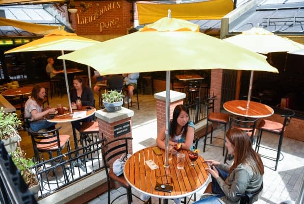 People in groups of two have drinks on an outdoor patio at The Lieutenant's Pump pub in Ottawa as patios opened in June. Indoor dining is set to open on Friday. (Justin Tang/The Canadian Press - image credit)