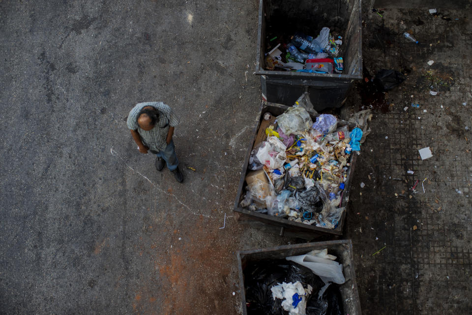 A homeless man walks next to trash dumpsters in Beirut, Lebanon, Sunday, July 12, 2020. Lebanon should quickly form a reform-minded government to carry out badly needed reforms to help get the tiny country out of its severe economic crisis where the Real GDP growth is projected to contract nearly 20% in 2020 and a crash in local currency led to triple-digit inflation rates, the World Bank said Tuesday. (AP Photo/Hassan Ammar)