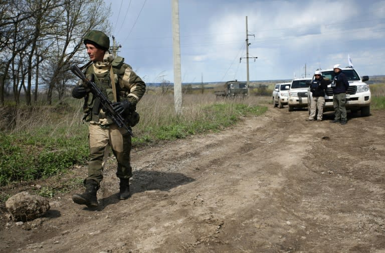 An armed pro-Russian separatist of the self-proclaimed Lugansk People's Republic walks past a convoy of the OSCE near Lugansk, on April 25, 2017