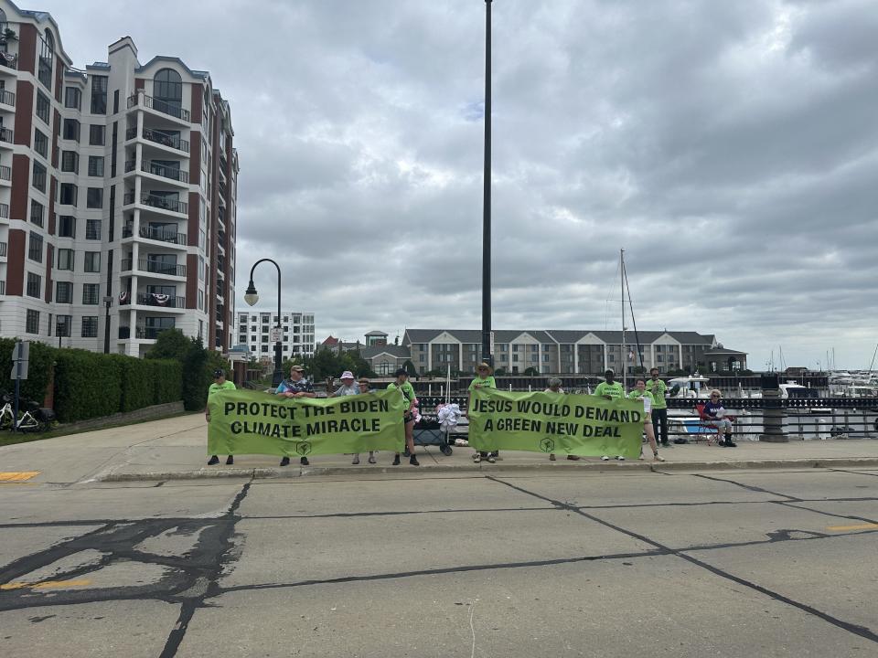 Protestors across the street from attendees lining up for Trump rally in Racine held a banner that read “Protect the Biden Climate Miracle.”