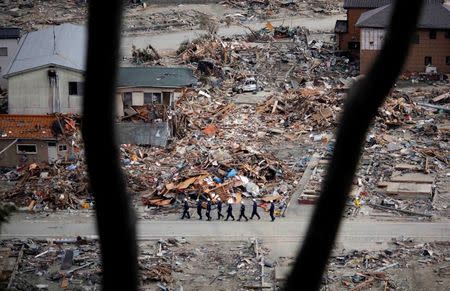 Members of a search and rescue team walk in an area destroyed by the March 11 earthquake and tsunami in Ishinomaki, northern Japan in this April 4, 2011 file photo. REUTERS/Carlos Barria/Files