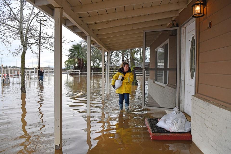 Stephanie Beard, of Brentwood, carries a sand bag to her flooded home on Bixler Road in Brentwood, California, on January 16 (@BAY AREA NEWS GROUP 2023)