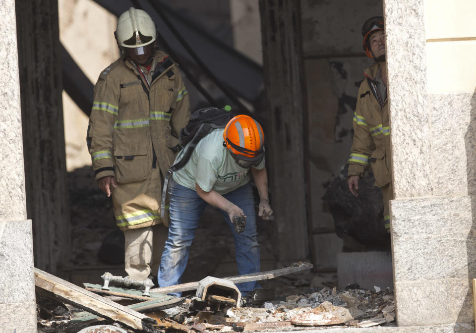 A National Museum worker inspects the charred rubble after an overnight fire at the museum in Rio de Janeiro, Brazil, Monday, Sept. 3, 2018. The esteemed museum houses artifacts from Egypt, Greco-Roman art and some of the first fossils found in Brazil. (AP Photo/Silvia Izquierdo)