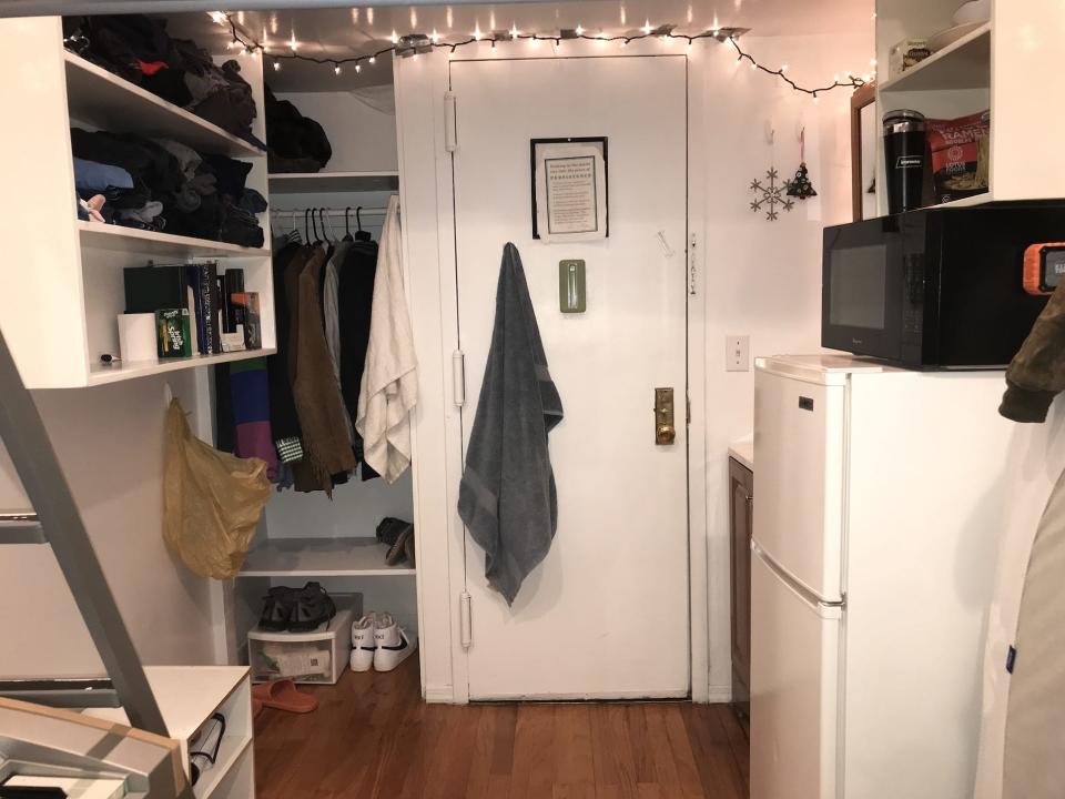 The interior of Axel Webber's apartment, with a door, string lights, closet, and mini fridge