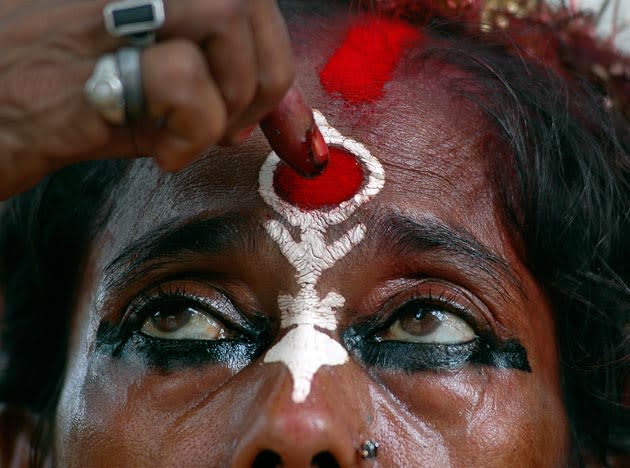 A sadhu or Hindu holy woman paints vermilion on her face during Ambubasi festival at Kamakhya temple, in Gauhati, India, Saturday, June 21, 2008. The Ambubasi festival will start on June 22. (AP Photo/Anupam Nath)