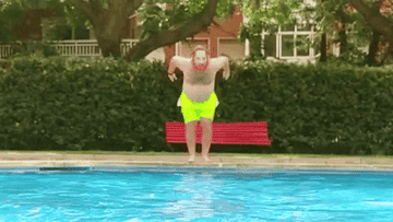 A man starfish jumps into the pool and makes a big splash