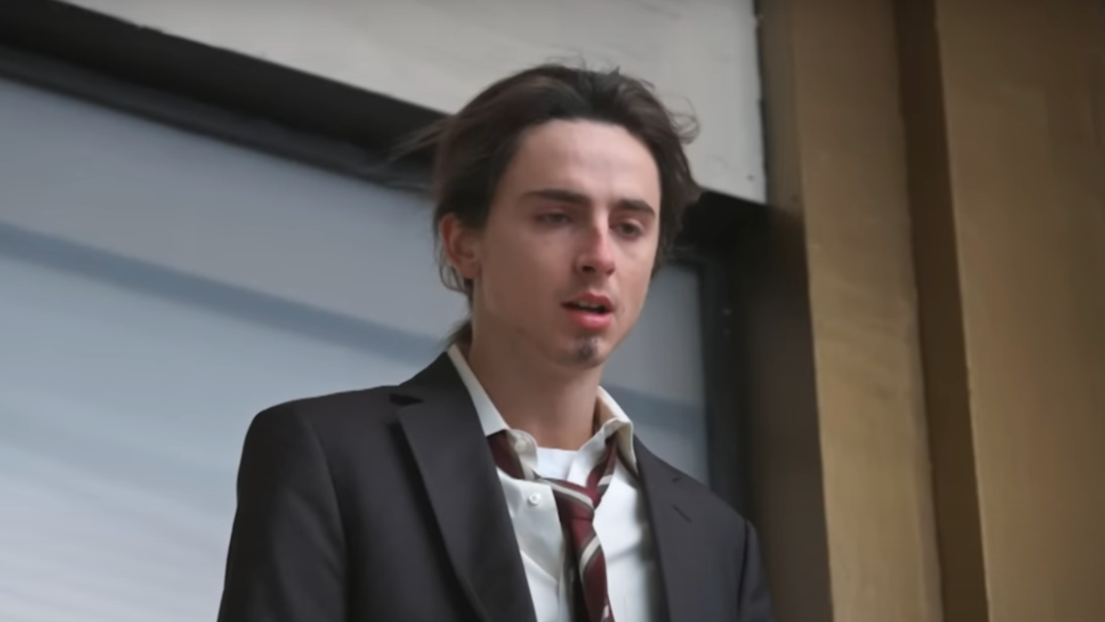  Timothee Chalamet in a suit on the edge of a window during an SNL sketch. 