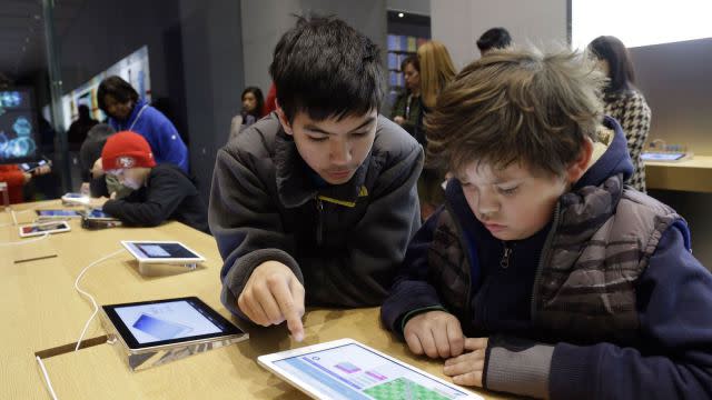 Matthew Triska, 13, center, helps Alex Fester, 10, to build code using an iPad at a youth workshop at the Apple store on Wednesday, Dec. 11, 2013, in Stanford, Calif. Apple stores nationwide were participating in computer science education week Wednesday, part of a joint effort with code.org to teach children the basics of coding. (AP Photo/Marcio Jose Sanchez)