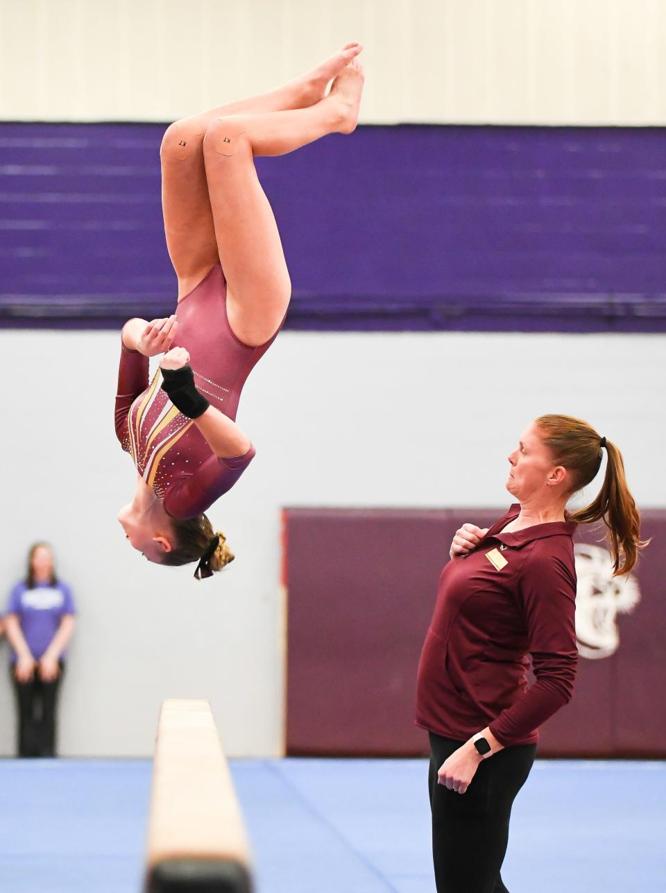 Bloomington North’s Jessica Floyd competes on the beam as head coach Andrea Smith watches during the gymnastics meet against Bloomington South and Edgewood at South on Monday, Jan. 8, 2024.