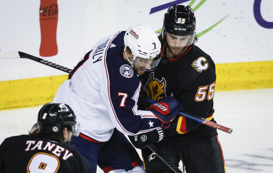 Columbus Blue Jackets forward Sean Kuraly (7) is checked by Calgary Flames defenseman Noah Hanifin (55) during the second period of an NHL hockey game Thursday, Jan. 25, 2024, in Calgary, Alberta. (Jeff McIntosh/The Canadian Press via AP)