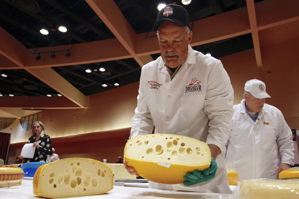 Steve Stettler holds a wheel of baby Swiss cheese at the biennial World Championship Cheese Contest, Tuesday, March 3, 2020, at the Monona Terrace Convention Center in Madison, Wis. It's the largest technical cheese, butter and yogurt competition in the world. This year the competition had a record 3,667 entries from 26 nations. (AP Photo/Carrie Antlfinger)