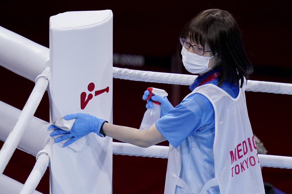 A cleaning crew worker wipes down the ring before the men's heavyweight 91kg boxing match at the 2020 Summer Olympics, Friday, July 30, 2021, in Tokyo, Japan. (AP Photo/Frank Franklin II)