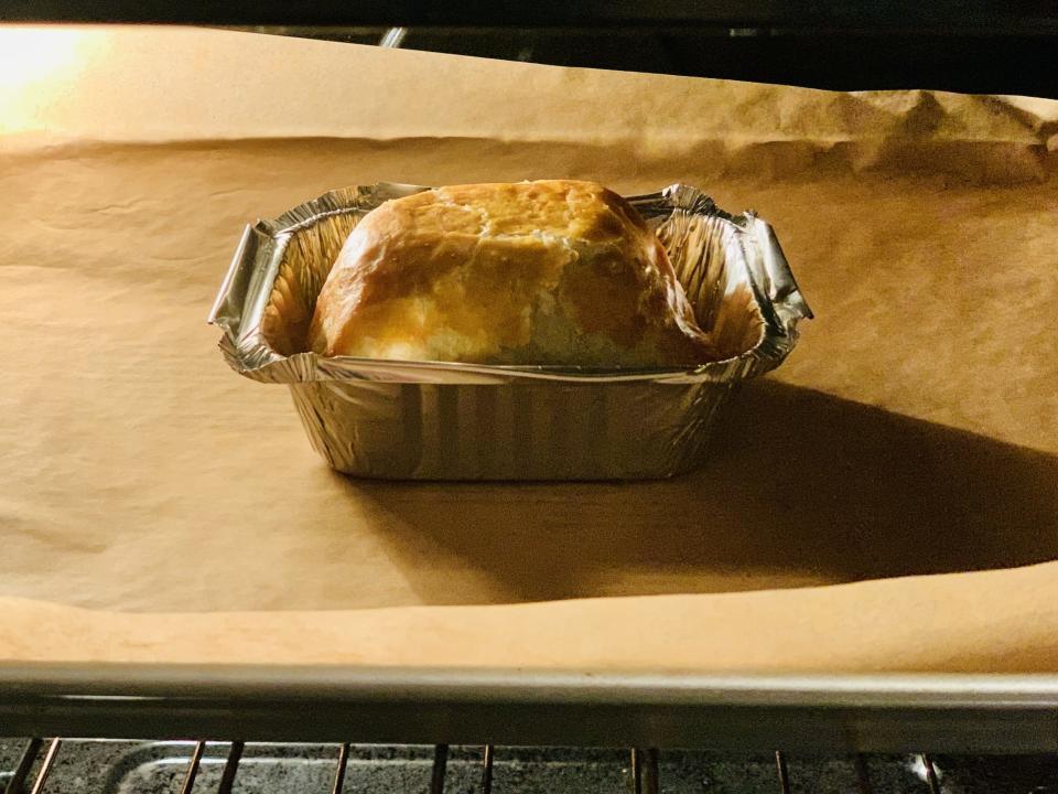 Beef Wellington from Alinea in metal takeout container on lined baking sheet in oven