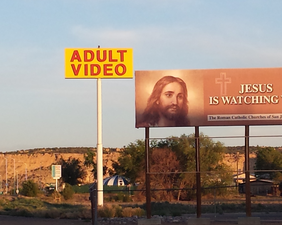 An adult video billboard next to a Jesus billboard.