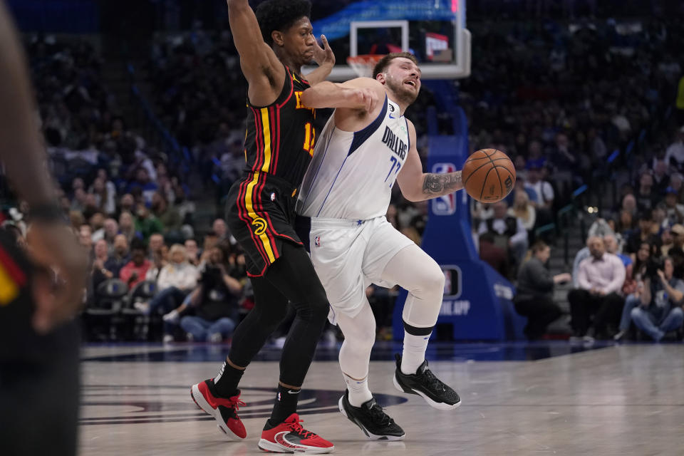 Dallas Mavericks guard Luka Doncic (77) gets some hard defense from Atlanta Hawks forward De'Andre Hunter (12) during the first quarter of an NBA basketball game in Dallas, Wednesday, Jan. 18, 2023. (AP Photo/LM Otero)