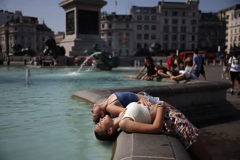 Dos mujeres sumergen la cabeza en la fuente para refrescarse en Trafalgar Square el 19 de julio de 2022 en Londres, Reino Unido