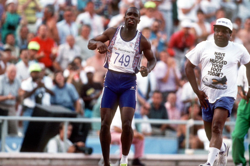 Great Britain's Derek Redmond (l) limps around the track toward the finish line after tearing his hamstring as his dad Jim (right) races after him to offer help. (Photo by S&G/PA Images via Getty Images)