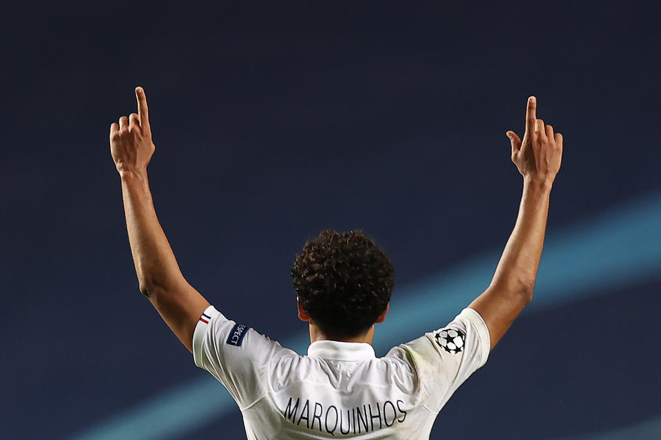 Marquinhos raises his arms in celebration. The photo is taken from behind him.