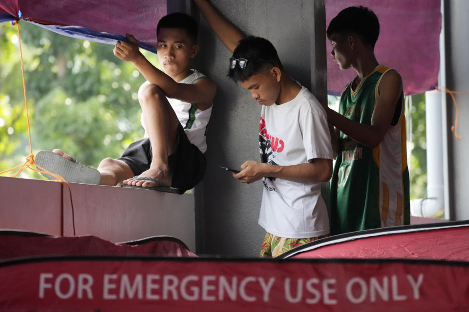 Evacuees watch to catch a glimpse of Philippine President Ferdinand Marcos Jr. as he visits an evacuation center in Guinobatan town, Albay province, northeastern Philippines, Wednesday, June 14, 2023. A gentle eruption of the Philippines' most active volcano that has forced nearly 18,000 people to flee to emergency shelters could last for months and create a protracted crisis, officials said Wednesday. (AP Photo/Aaron Favila)