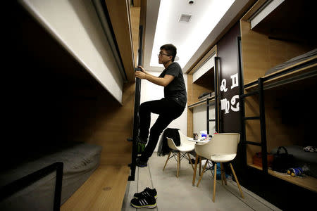 Du Xianchang, a R&D engineer at BaishanCloud, climbs up a ladder as he goes to bed in an individual sleeping quarter in the office after finishing work at midnight, in Beijing, China, April 27, 2016. REUTERS/Jason Lee