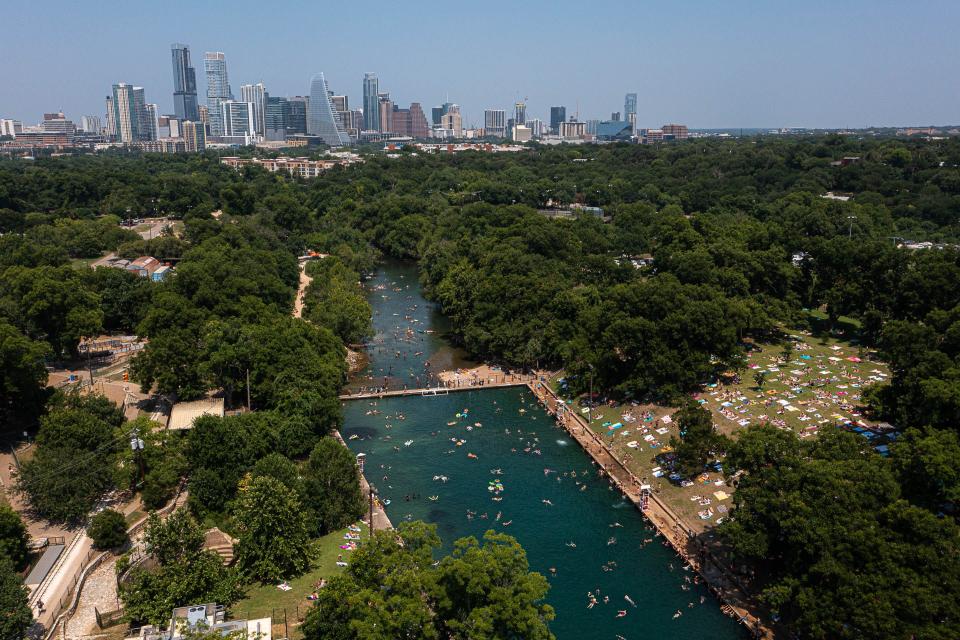 Hundreds of visitors play in the water and lie on the grass at Barton Springs Pool on Monday. The forecast isn't getting any better; the National Weather Service predicted a maximum heat index of 119 degrees Tuesday in Austin.