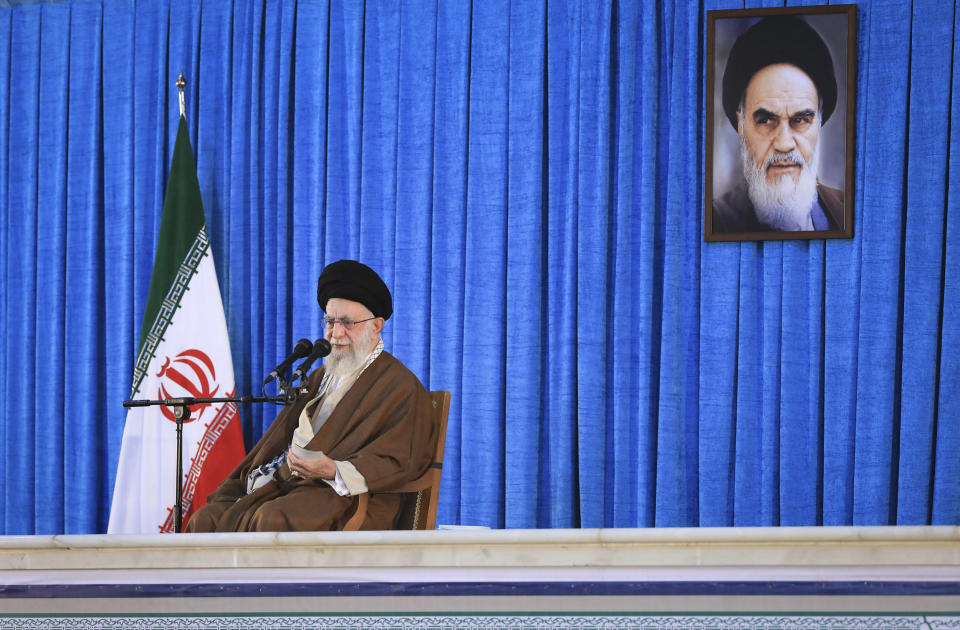 In this picture released by an official website of the office of the Iranian supreme leader, Supreme Leader Ayatollah Ali Khamenei speaks during a ceremony commemorating the death anniversary of the late revolutionary founder Ayatollah Khomeini, shown in the poster at top right, at his mausoleum just outside Tehran, Iran, Sunday, June 4, 2023. (Office of the Iranian Supreme Leader via AP)