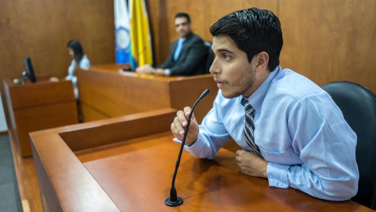 Portrait of a male witness addressing the courtroom in a trial - legal system concepts.