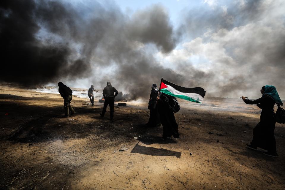 <p>Palestinians set tires on fire in response to Israel’s intervention during a protest organized to mark 70th anniversary of Nakba, also known as Day of the Catastrophe in 1948, and against the United States’ relocation of its embassy from Tel Aviv to Jerusalem, near the Gaza-Israel border in Khan Younis on May 14, 2018. (Photo: Mustafa Hassona/Anadolu Agency/Getty Images) </p>