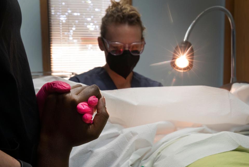 A nurse holds the hand of a patient as she undergoes an abortion at the Women's Med Center in Kettering, near Dayton, Ohio, Thursday, June 30, 2022. The woman, who had traveled from Kentucky, was only a little over five weeks. No heartbeat had been detected during her sonogram. When Roe vs. Wade was overturned a week ago by the Supreme Court, Kentucky shut down all abortions because of trigger laws.