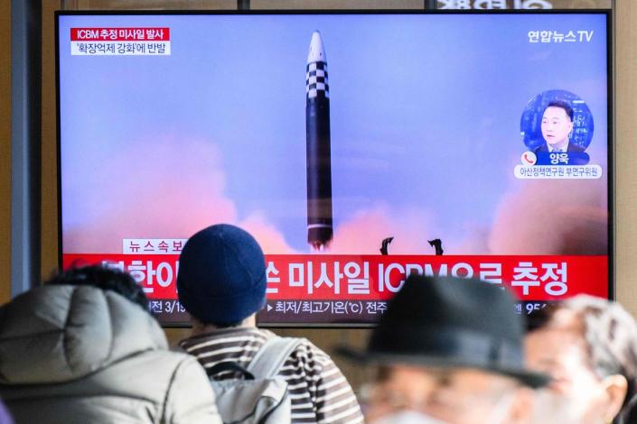 People sit near a television showing a news broadcast with file footage of a North Korean missile test, at a railway station in Seoul (AFP via Getty Images)