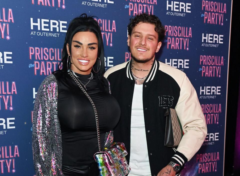 katie price and jj slater, a woman and man smile at the camera, she has long black hair and wears a black top with silver jacket, he has short curly brown hair and wears a white tshirt with sports jacket